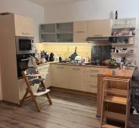 Küche in einer 4-Zimmer-Wohnung mit Holzboden, Kinderstuhl und Spielzeug.