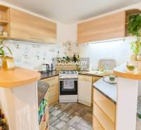 Eine Küche in einem Einfamilienhaus mit einer Eckküche und Holzmuster, dekorativen Pflanzen auf den Regalen.