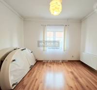 Ein Raum mit Holzboden in einem Einfamilienhaus, helle Dekoration und großes Fenster.