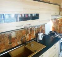 Ein Zimmer in einer 2-Zimmer-Wohnung mit einem Boden in Holzdekor, einem Fernseher und Einbauschränken.