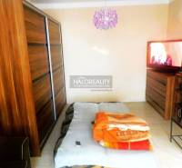 Schlafzimmer in einer 2-Zimmer-Wohnung mit Bett, Sofa und Schrank mit Holzdekor.