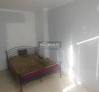 Schlafzimmer mit Metallbett und weißen Wänden in einer Zweizimmerwohnung.