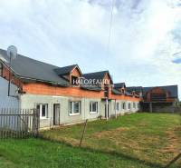 Gewerberäume in Tibava, ein unvollendetes Gebäude mit einer Rasenfläche und einem Zaun.