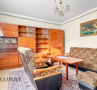 Wohnzimmer in einem Einfamilienhaus mit Sesseln, Teppich, Bücherregal und Vorhängen.