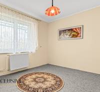 Ein Zimmer in einem Einfamilienhaus mit einem hellen Teppich, Vorhängen und einem Wandbild.