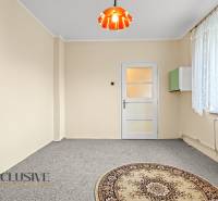 Ein helles Zimmer in einem Einfamilienhaus mit Teppichboden und einem Fenster mit Spitzenvorhang.