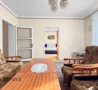 Einfamilienhaus mit Wohnzimmer, Blumeneinrichtung, Couchtisch und einem Bild an der Wand.