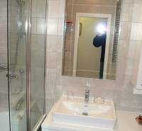 Badezimmer mit Dusche, Spiegel und Waschbecken in einer 4-Zimmer-Wohnung.