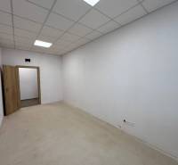 Innenraum eines Büros mit weißen Wänden, abgehängter Decke und offenen Türen.