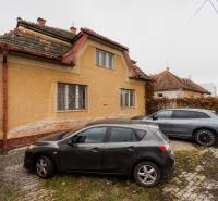 Ein Einfamilienhaus in der Partizánska-Straße in Bánovce nad Bebravou mit zwei Autos, die davor geparkt sind.