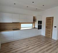 Küche mit weißen Schränken und Holzelementen in einem Einfamilienhaus, Boden mit Holzdekor.