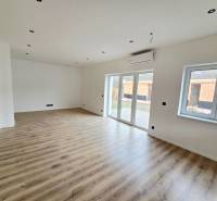 Innenraum eines Einfamilienhauses mit Holzboden und großen Fenstern.