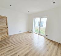 Innenraum eines Einfamilienhauses mit Holzboden und großem Fenster zum Garten.