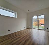 Innenraum eines Einfamilienhauses mit Holzboden und großem Fenster.