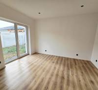 Ein Zimmer in einem Einfamilienhaus mit Glastüren und einem Boden in Holzoptik.