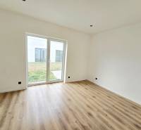 Innenraum eines Einfamilienhauses mit weißen Wänden, Boden in Holzoptik und großem Fenster.