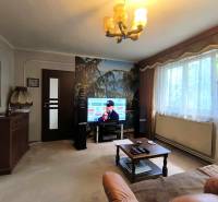 Wohnzimmer mit Fernseher, Sofa, Tisch und großem Fenster, Einfamilienhaus.