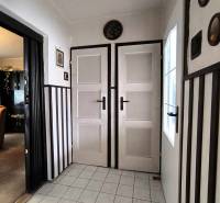 Innenraum eines Einfamilienhauses mit weißen Türen, Fliesenboden und dunkler Wandverkleidung.