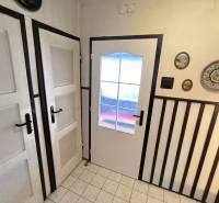 Das Innere eines Einfamilienhauses mit weißen Türen, Wanddekorationen und Fliesen.