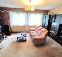 Wohnzimmer in einem Einfamilienhaus mit braunem Sofa, Schränken und einem Fernseher an der Wand.