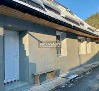 Ein Einfamilienhaus in Hronec mit Schnee auf dem Dach, einer weißen Tür und einer Holzbank.