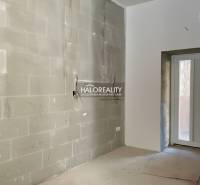 Heller Raum mit unfertigen Wänden in einem Einfamilienhaus mit Eingangstür.