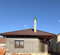 Ein Einfamilienhaus im Bau in Cífer mit einem braunen Dach und einem Schornstein.