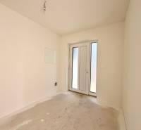 Ein leerer Raum mit französischen Türen in einem Einfamilienhaus, weiße Wände, Betonboden.