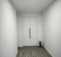 Ein weißer Raum mit Holzboden und Doppeltüren in einer Vierzimmerwohnung.