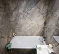 Badezimmer mit grauen Marmorkacheln und Badewanne in einer 4-Zimmer-Wohnung.