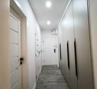 Flur mit vielen Einbauschränken und einem Boden mit Holzdekor in einer 4-Zimmer-Wohnung.