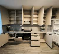 Küche in einer 4-Zimmer-Wohnung mit Holzboden, offenen Regalen und Geräten.