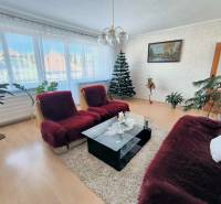 Wohnzimmer in einem Einfamilienhaus mit Sofa, Teppich, Pflanzen, Bild und Holzboden.