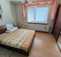 Ein Schlafzimmer in einem Einfamilienhaus mit einem Bett, einem Schrank und einem Boden mit Holzdekor.