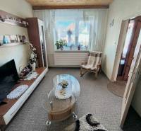 Wohnzimmer in einem Einfamilienhaus mit Teppich, Fernseher und Glastisch.