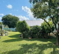 Der Garten eines Einfamilienhauses in Partizánske mit gepflegtem Rasen, Bäumen und einer Sitzecke.