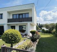 Ein Einfamilienhaus in Partizánske, umgeben von einem Garten mit Bäumen und grünem Rasen.