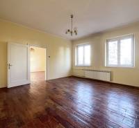 Ein geräumiges Zimmer mit einem Holzboden und zwei großen Fenstern.