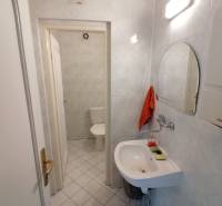 Badezimmer in Büros mit Spiegel, Waschbecken und Toilette auf weißen Fliesen.