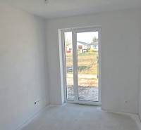 Ein weißer Raum in einem Einfamilienhaus mit einem großen Fenster und Blick auf den Garten.