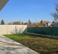 Der Garten eines Einfamilienhauses in Piešťany mit Rasen, Betonterrasse und Umzäunung.