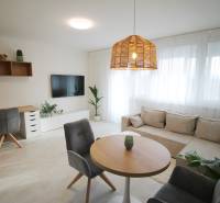 Helles Wohnzimmer mit Sofa, Couchtisch, Arbeitsecke und Holzboden.