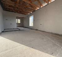 Innenraum eines Einfamilienhauses mit Betonboden, Holzbalken und Elektroinstallationen.