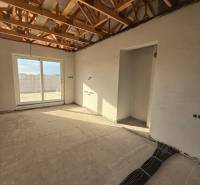 Innenraum eines Einfamilienhauses mit freiliegenden Deckenbalken und vorbereiteter Elektroinstallation.