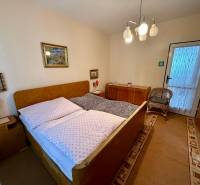 Schlafzimmer in einer 2-Zimmer-Wohnung mit gepolstertem Bett, Teppichboden und dekorativen Bildern.