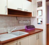 Küchenecke in einem Einzimmerapartment mit Spüle und Schränken.