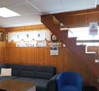 Innenraum einer Hütte mit Holzverkleidung, Treppe, Sofa und Dekorationen an den Wänden.