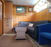 Wohnzimmer in einer Hütte mit Sofa, Sessel und Wandverkleidungen.