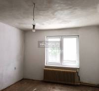 Ein leerer Raum in einem Einfamilienhaus mit weißen Wänden, einem Heizkörper und einem Fenster.