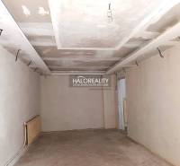 Neukončená miestnosť v rodinnom dome s bielymi stenami a tehlovou podlahou.